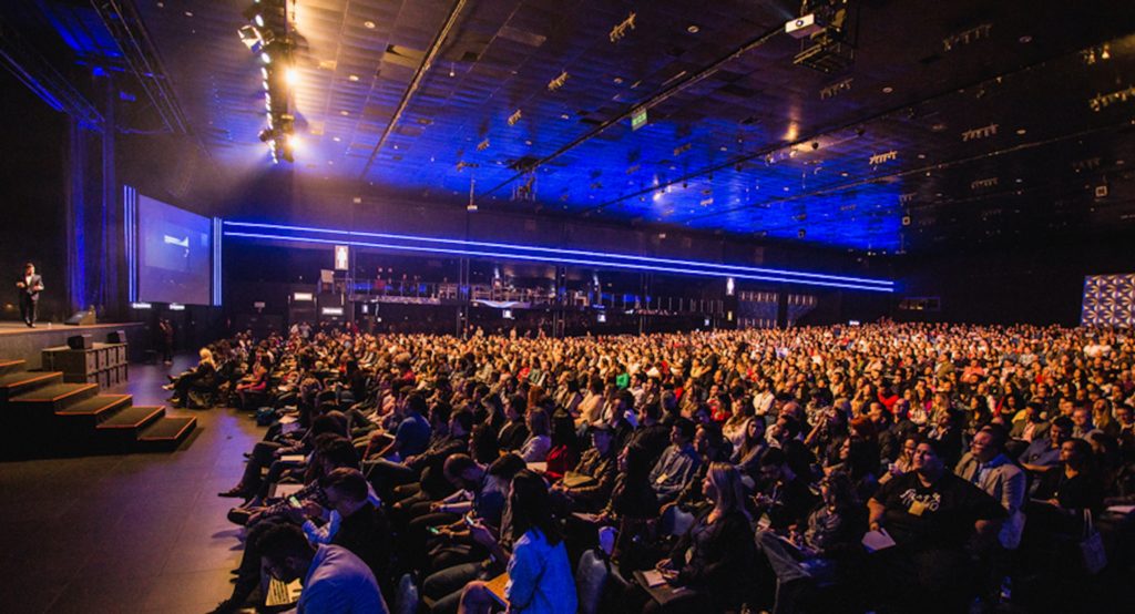 Voller Konferenzsaal mit Podest und Sitzplätzen