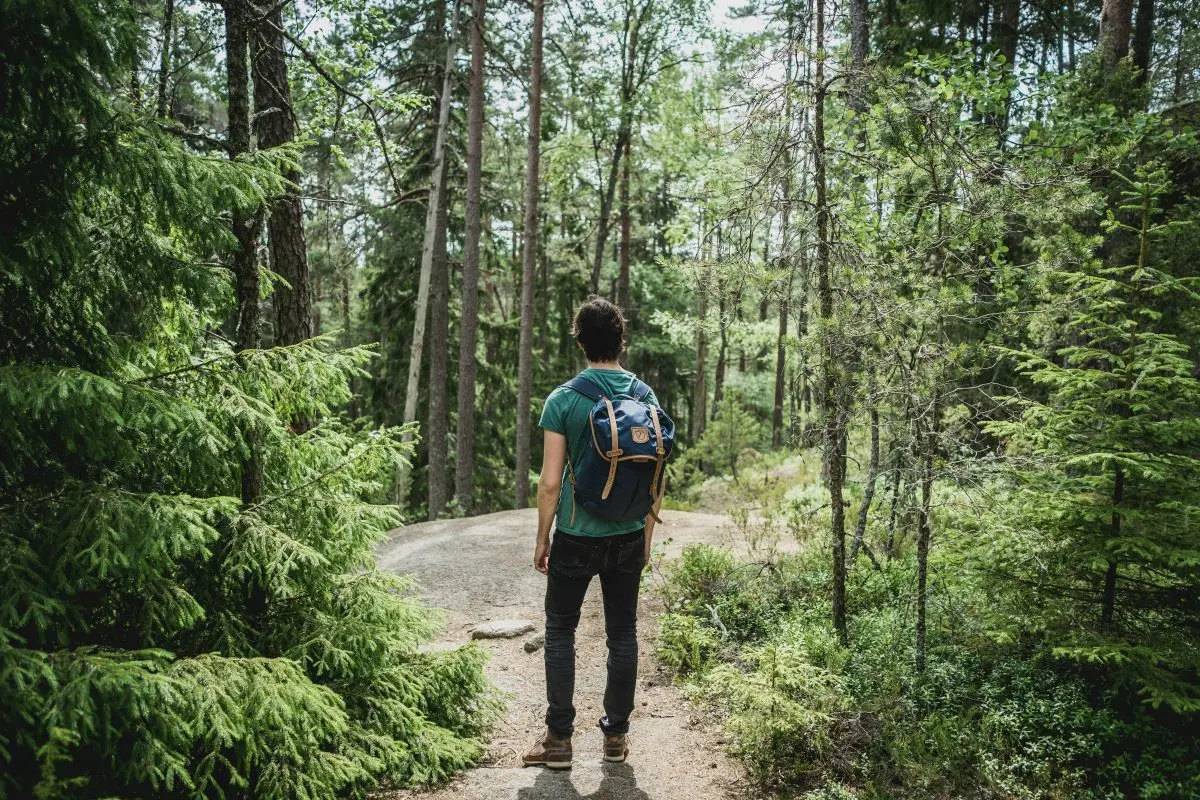 Mann mit Rucksack steht in einem Wald.