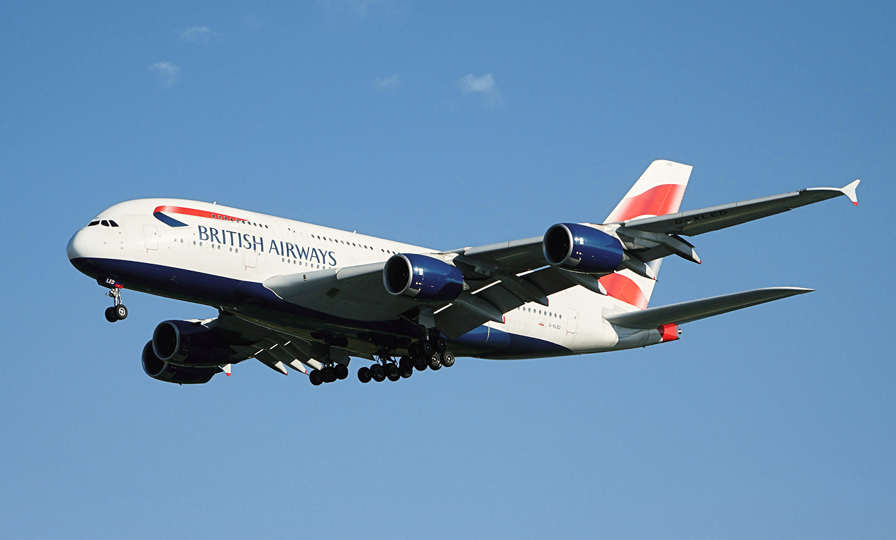 British Airways Airbus A380 in flight, showing its landing gear extended against a clear blue sky.