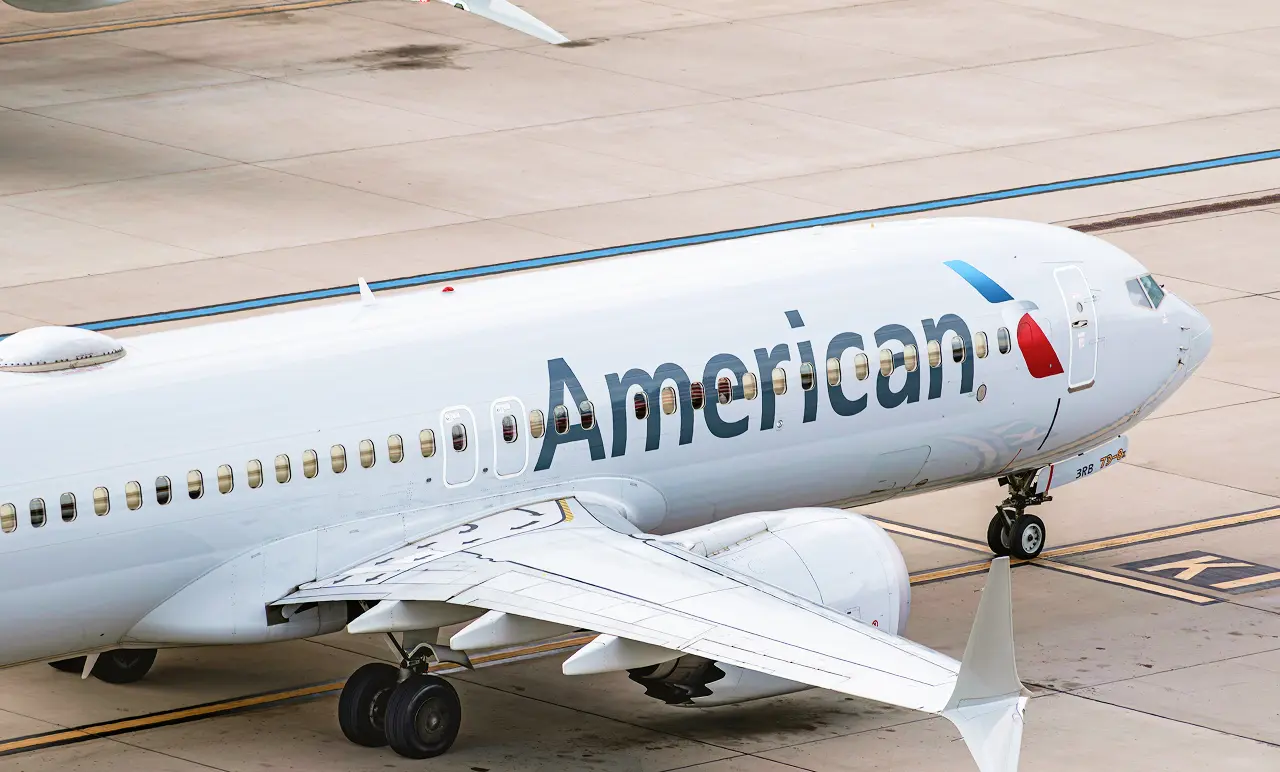 An airplane on a runway, featuring the American Airlines logo on its fuselage. The aircraft is preparing for departure or taxiing.