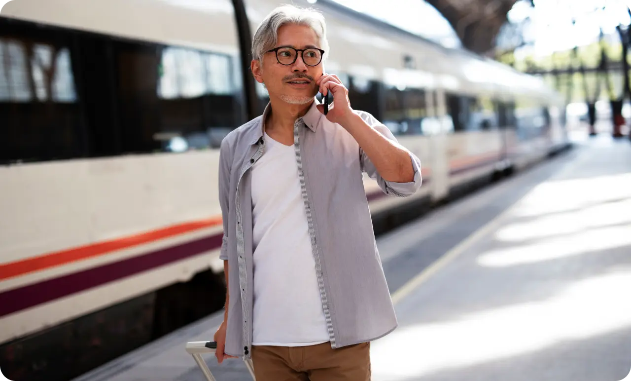 A male traveller with a rolling suitcase about to get on a train.
