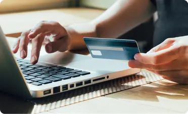 A person inputing their credit card details in a laptop.