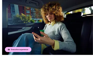 A driver holding a car door open for a woman as she gets into a car.