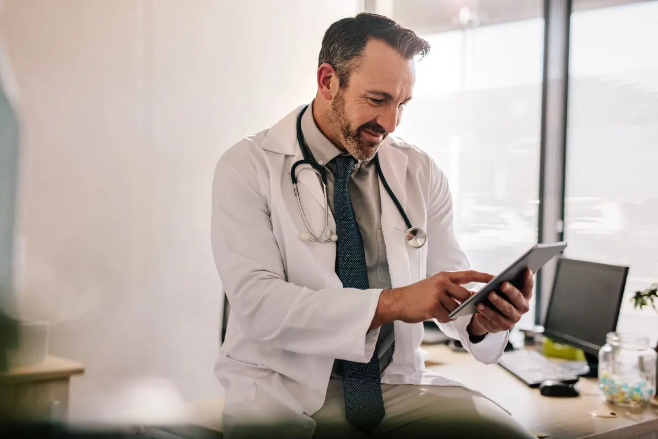 Arzt informiert sich am Tablet über Reiserisikomanagement-Unternehmen