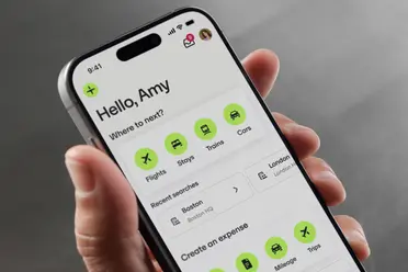 Close-up of a smartphone showing a travel app interface. It displays options for flights, stays, trains, and cars with recent searches listed.