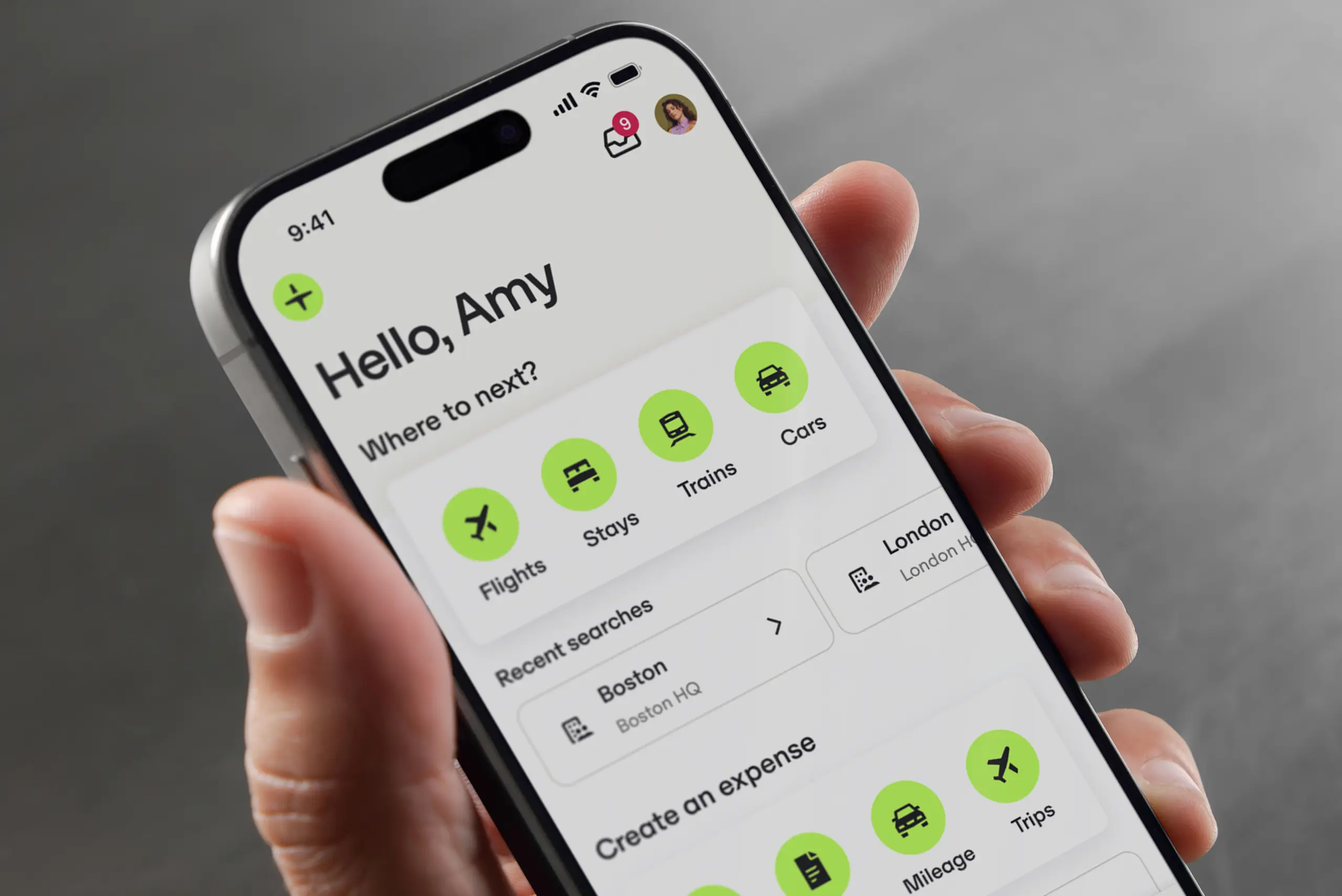 Person holding a smartphone displaying a travel app interface with options for flights, stays, trains, and cars, on a gray background.