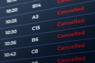 Flight information board showing multiple flights marked as "Cancelled" in red text.