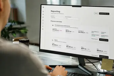Person viewing finance overview report on a computer screen, showing cancellation balance, refunds, total funds, and spending categories like flights and hotels.