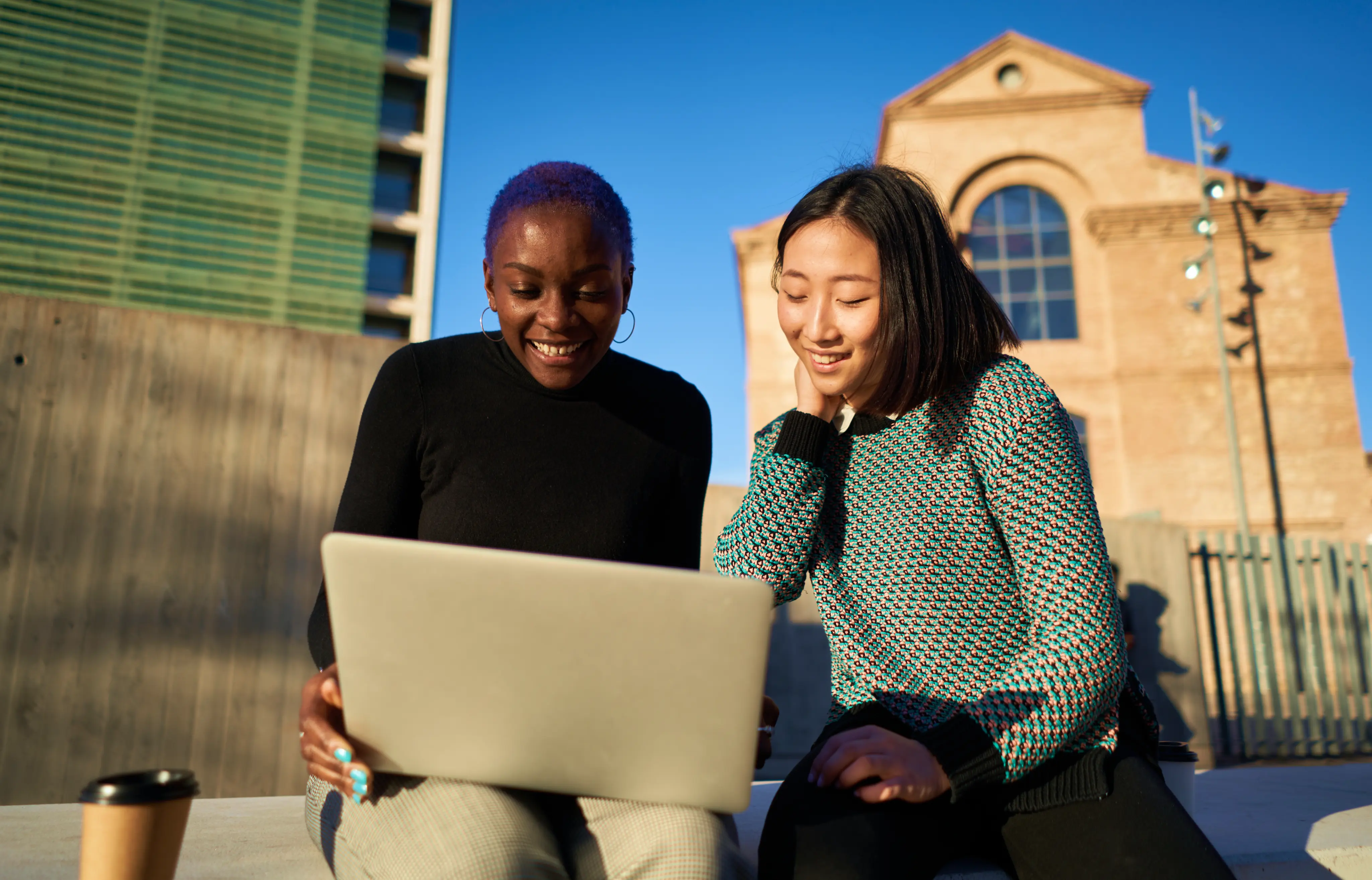 Diverse Coworkers Using Laptop Together On Street