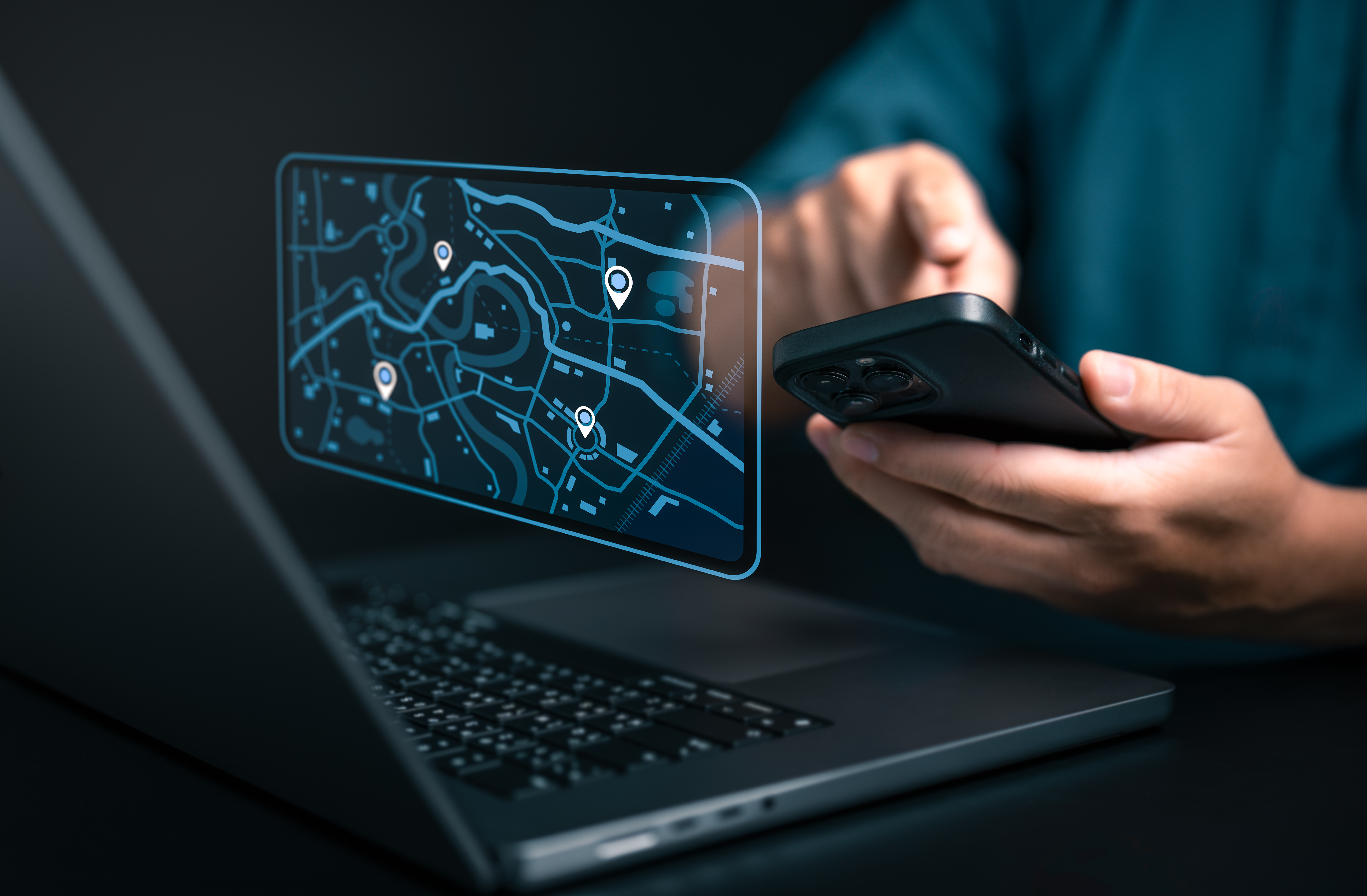 Handy und Laptop mit holografischer Karte, die beim Tracking von Mitarbeiter:innen hilft.