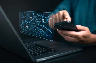 Handy und Laptop mit holografischer Karte, die dem Tracking von Mitarbeitenden dient.