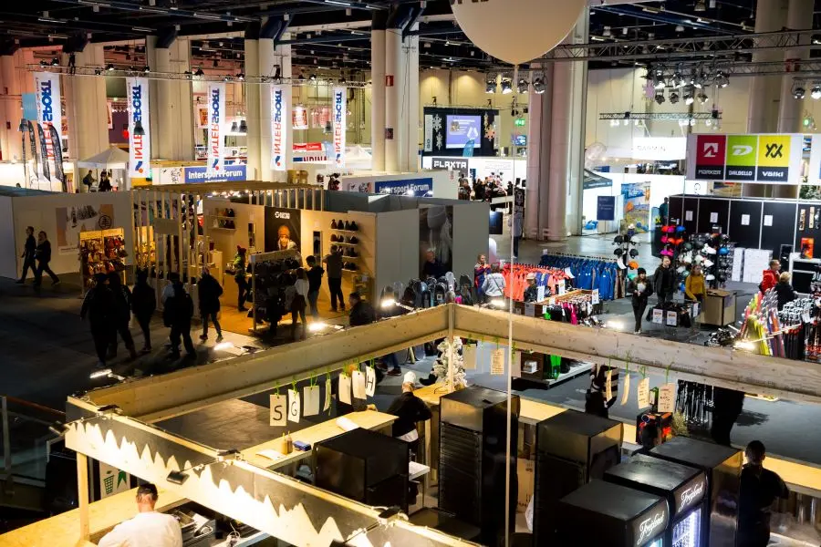 Messehalle mit Ständen und Besucher:innen