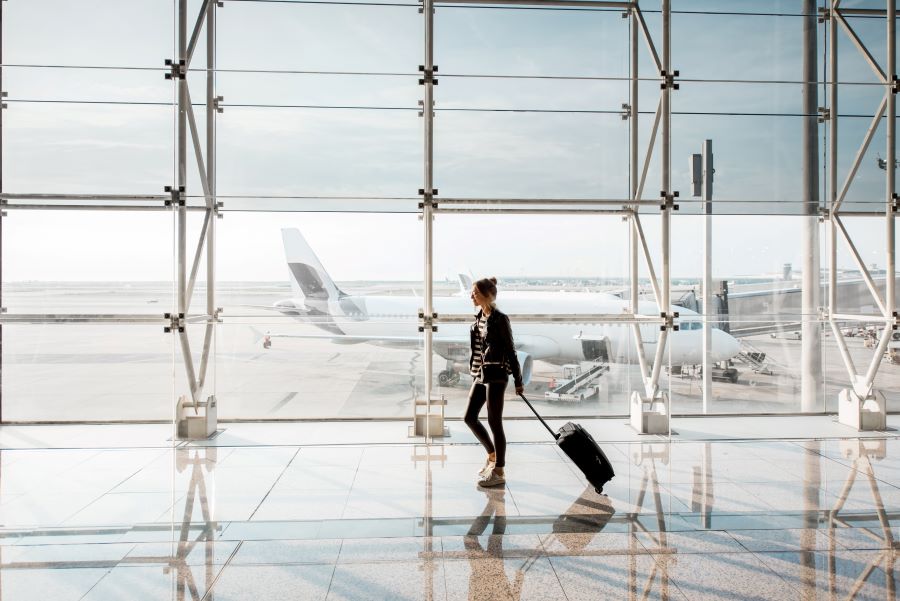 Eine Person zieht einen kleinen Koffer im Flughafen.