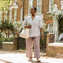 A woman walking past brick townhouses on a sunny London street
