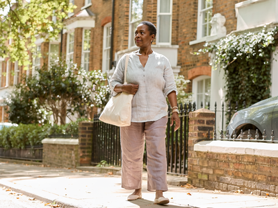 Woman in her fifties walking through an autumnal London park.