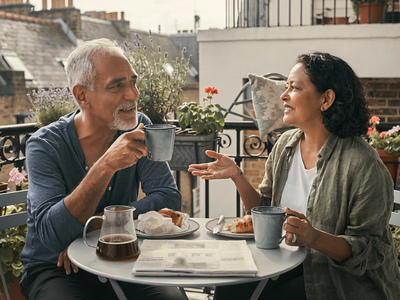 Couple in their fifties having breakfast together on a London balcony.
