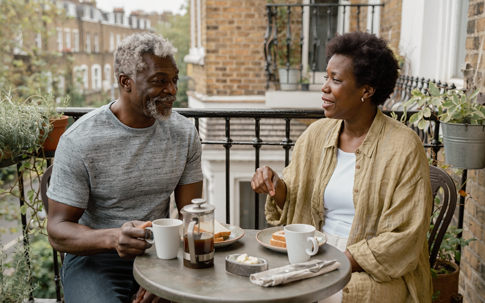 Couple in their fifties having breakfast together on a London balcony.