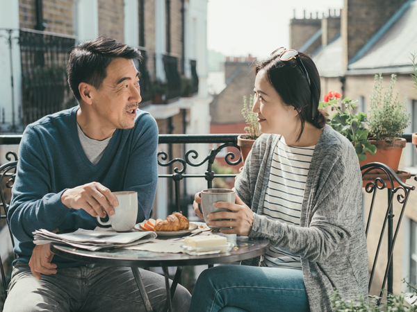 Couple in their fifties having breakfast together on a London balcony.