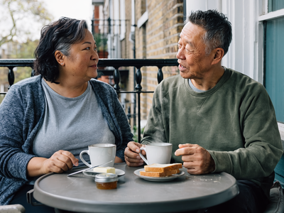 Couple in their fifties having breakfast together on a London balcony.