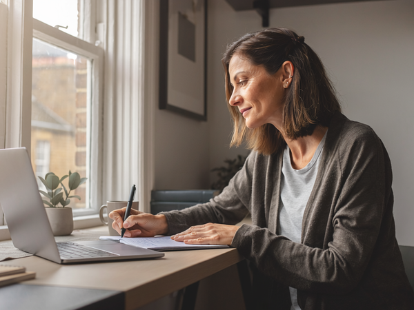 Adult at home, focused on a notebook in natural daylight.