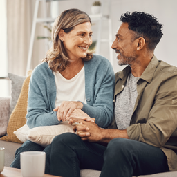 A mixed-heritage couple in their late 30s talking warmly together at home, hopeful about starting a family