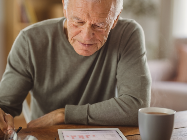 Man reviewing paperwork at a kitchen table with tea.