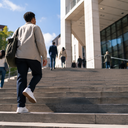 A person climbing the steps of a public health building.