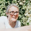 an older woman wearing glasses sitting on a bench