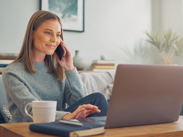 Young adult arranging an appointment by phone and laptop.