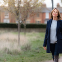A woman in her 40s walking outdoors looking calm and hopeful, soft daylight