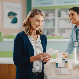 A person reading options at a UK pharmacy counter, everyday high-street setting