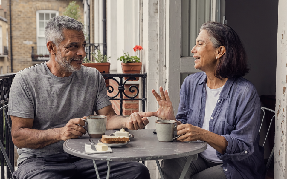 Couple in their fifties having breakfast together on a London balcony.