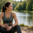 A woman resting beside a lake with a water bottle after exercise
