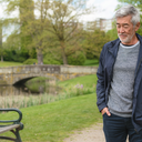 A man in his 50s on a relaxed daytime walk in a park, ordinary and dignified