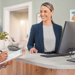 A young newcomer at a friendly GP reception desk completing a registration form, welcoming setting