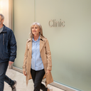 Two Londoners walking past a clinic frontage inside Westfield London on a bright weekday morning.