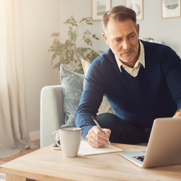 A man in his 40s comparing care options on a laptop in a bright living room, relaxed