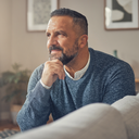 A Middle Eastern man in his 40s checking how he feels at home, hand resting thoughtfully, soft daylight