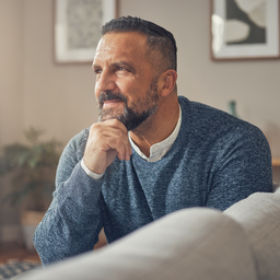 A Middle Eastern man in his 40s checking how he feels at home, hand resting thoughtfully, soft daylight