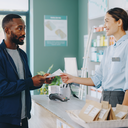 A person collecting a prescription at a UK community pharmacy counter, everyday high-street setting