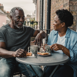 Couple in their fifties having breakfast together on a London balcony.