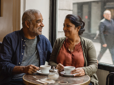 South Asian couple at a small London cafe by a window.