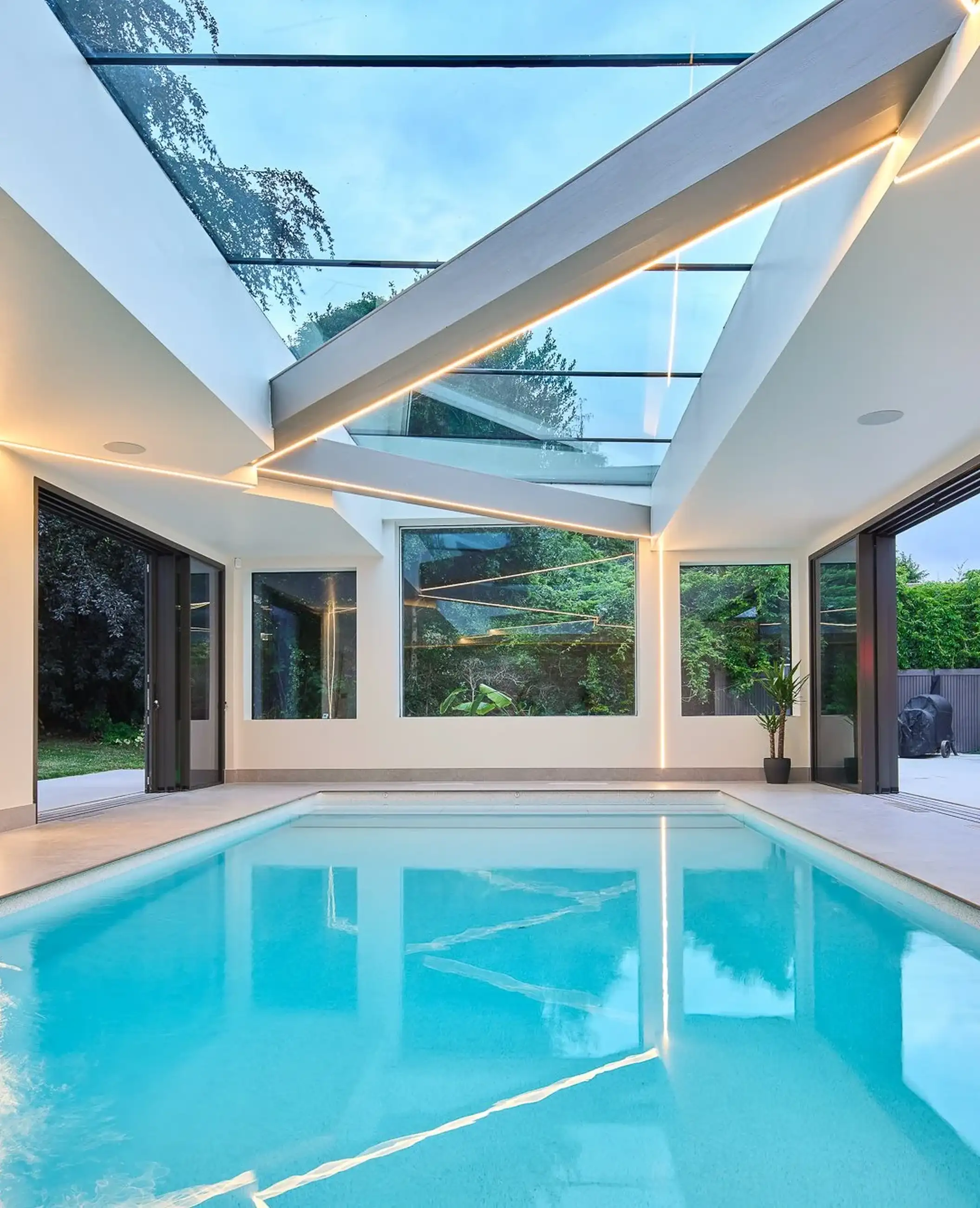Swimming pool glass roof at Three Rivers, six frameless panes over the pool with the garden windows below