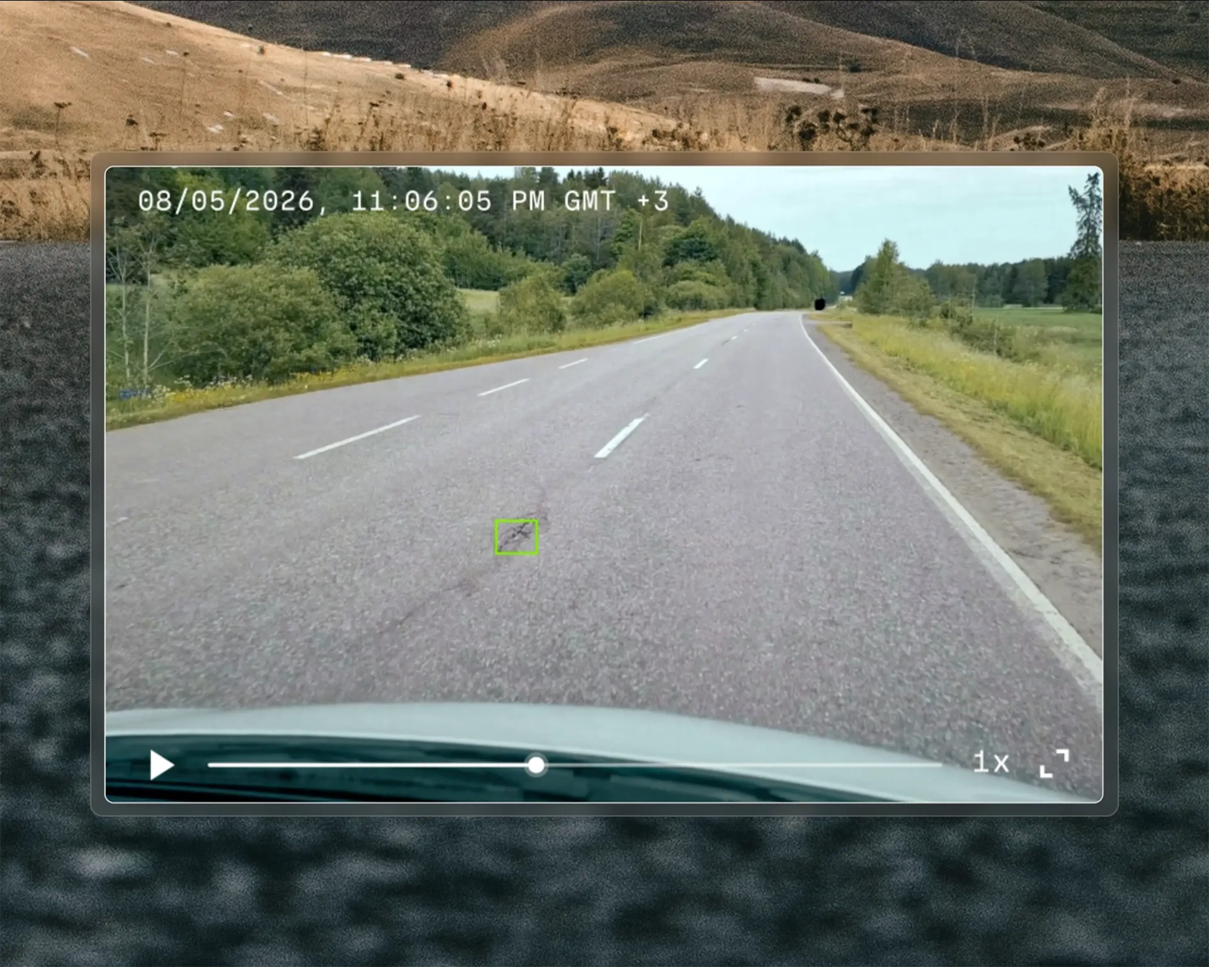 A dashcam view of a rural road surrounded by trees and fields, displaying date and time, with a pothole on the road highlighted..