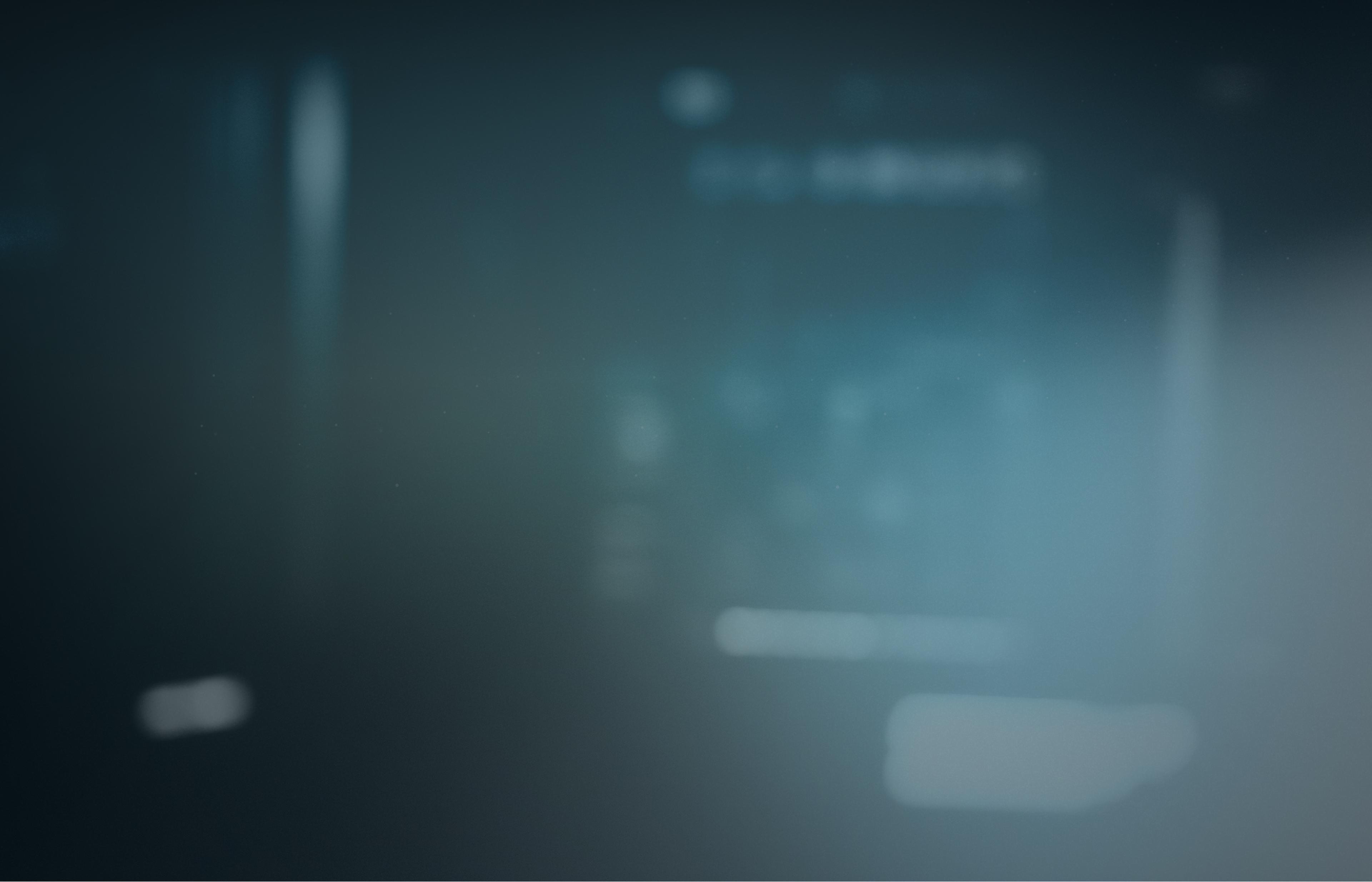 Blurred abstract background with dark blue and gray tones, featuring indistinct light and shadow patterns.