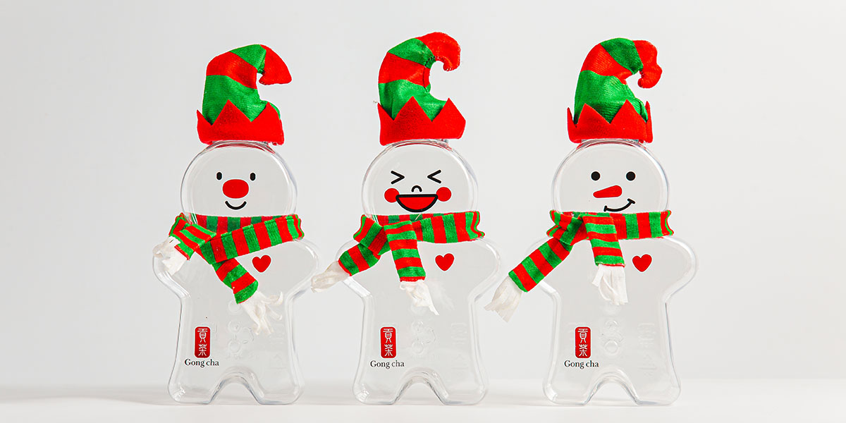 Three clear snowman-shaped cups wearing red-green elf hats and striped scarves, each with a small red heart and Gong Cha logo.