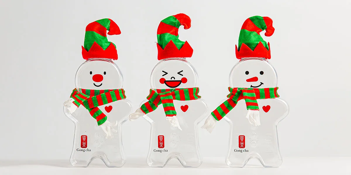 Three clear snowman-shaped cups wearing red-green elf hats and striped scarves, each with a small red heart and Gong Cha logo.