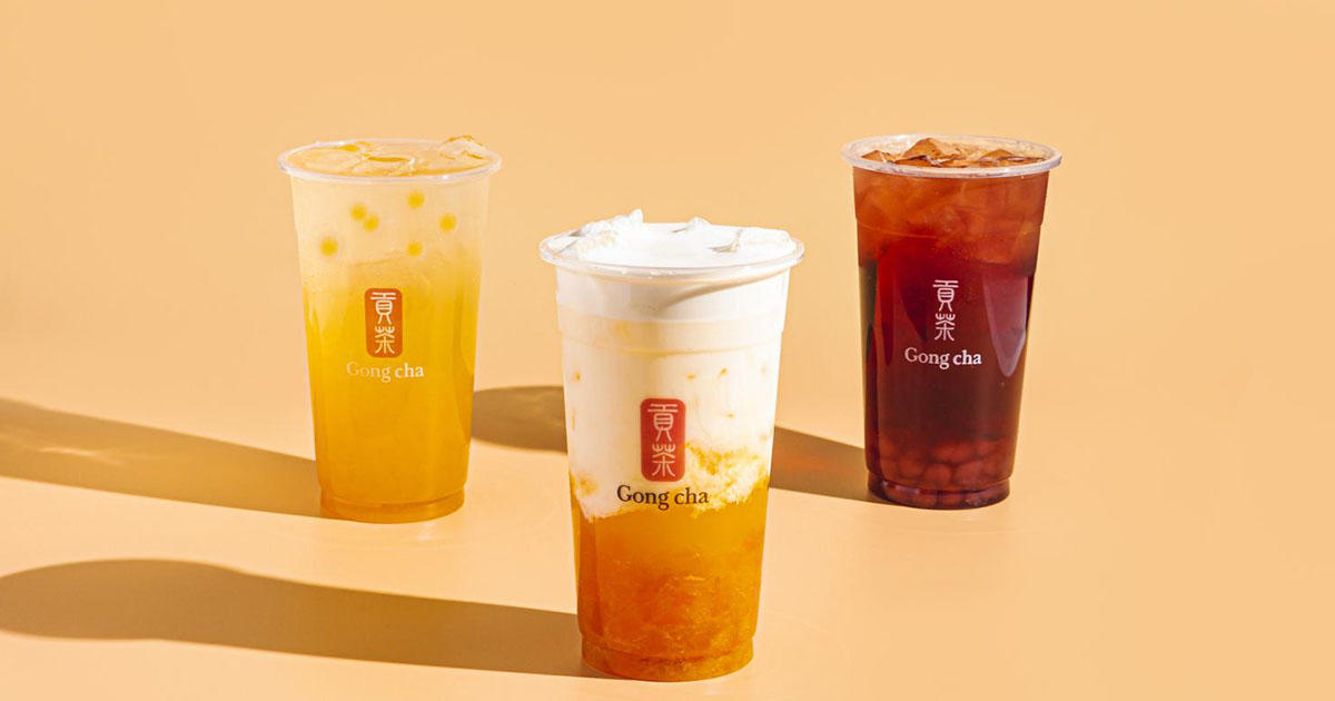 Three Gong Cha beverages on warm backdrop: mango fruit tea, cream-topped tea with fruit base, and iced black tea.