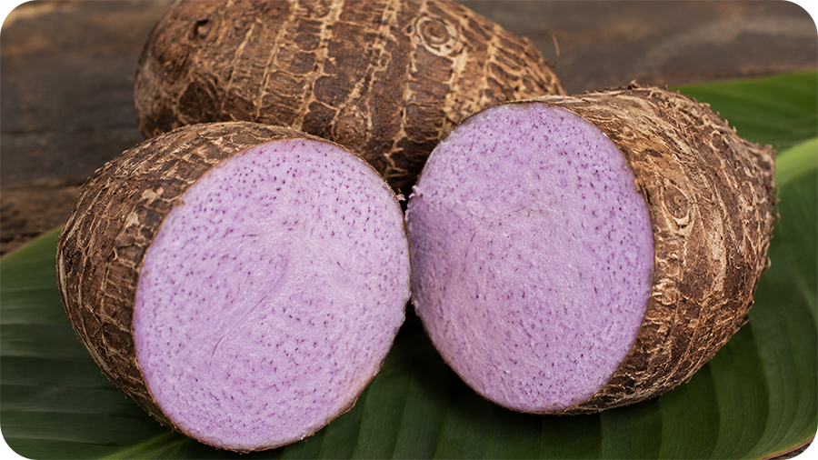 Raw taro root cut open showing pale purple flesh with natural purple speckling