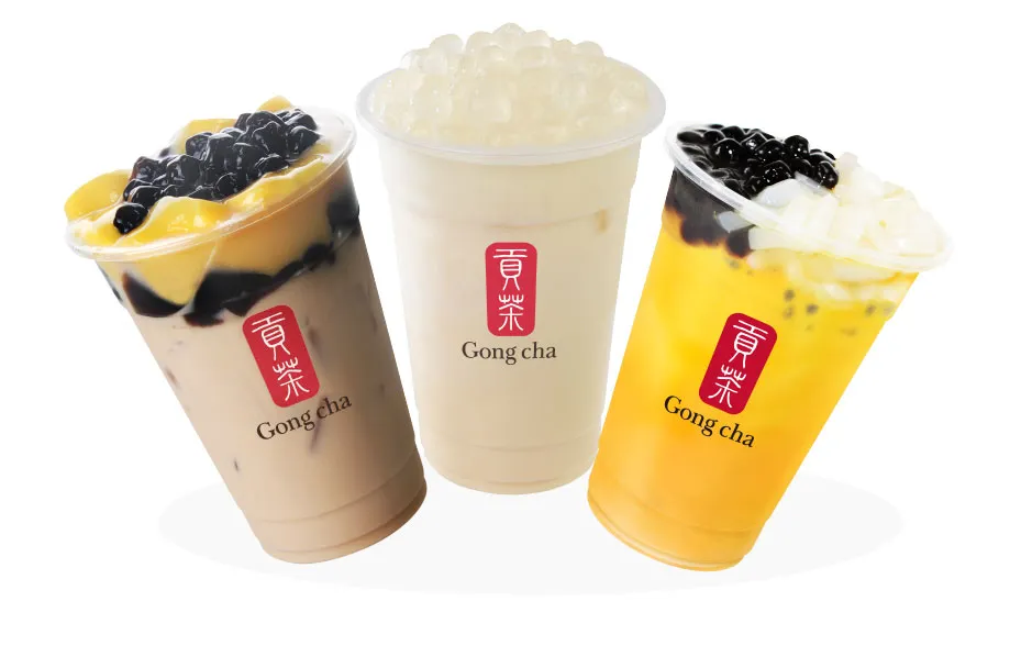 Three Gong Cha bubble teas with various toppings, including pearls and fruit pieces, in clear cups with red logos.